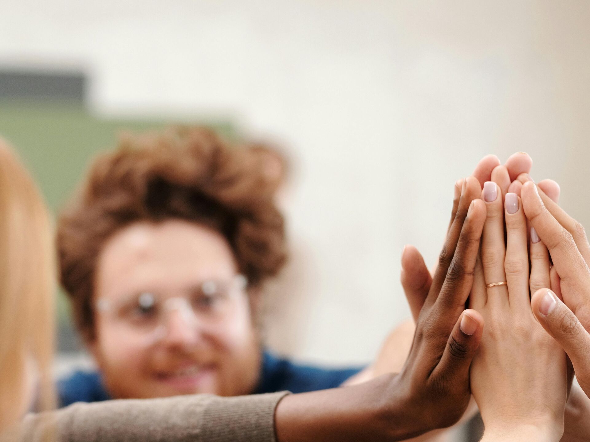 Mehrere Menschen geben sich ein gemeinsames High-Five als Zeichen für Teamgeist und Erfolg.